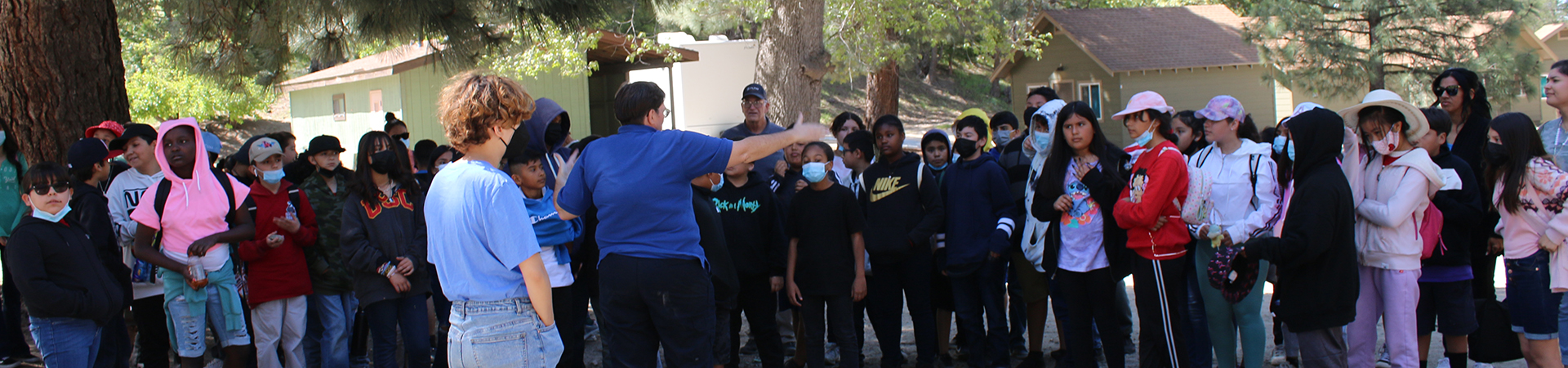  large group of kids at camp listening to an adult  