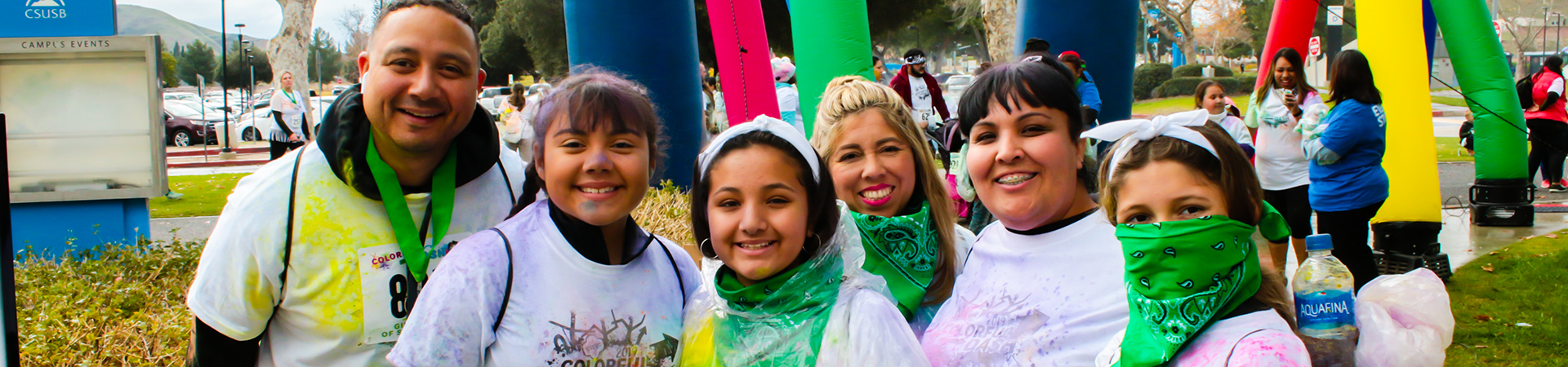  girl scouts and adults covered in colored powder and wearing green bandanas 